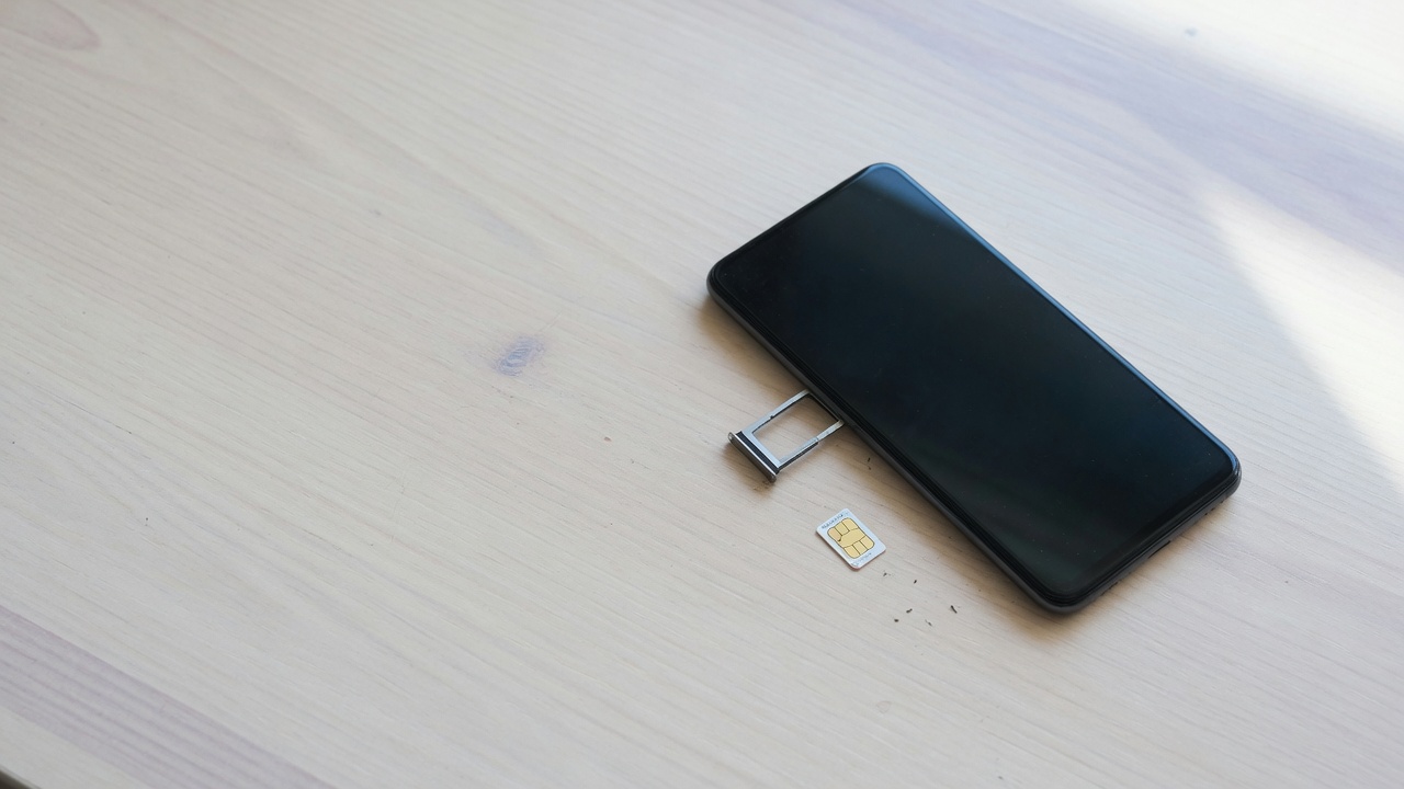 机の上に置かれたSIMカードとスマートフォン